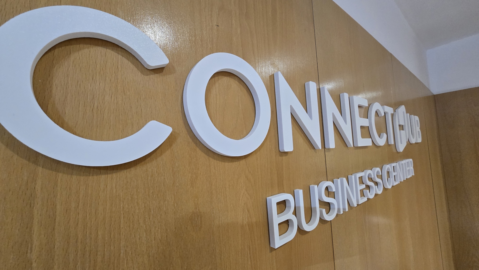 Letras da marca ConnectHub Business Center na parede de madeira