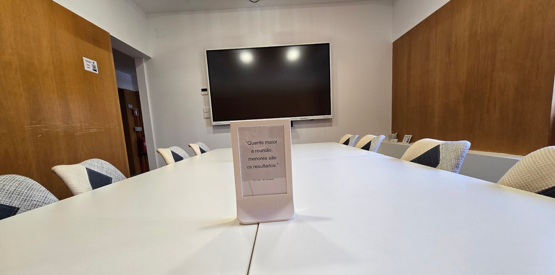 Mesa de reuniões da ConnectHub com ecrã interativo ao fundo
